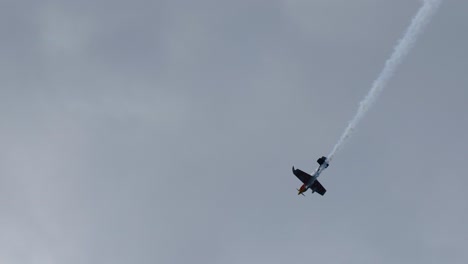 single plane executing aerial flips and smoke trails