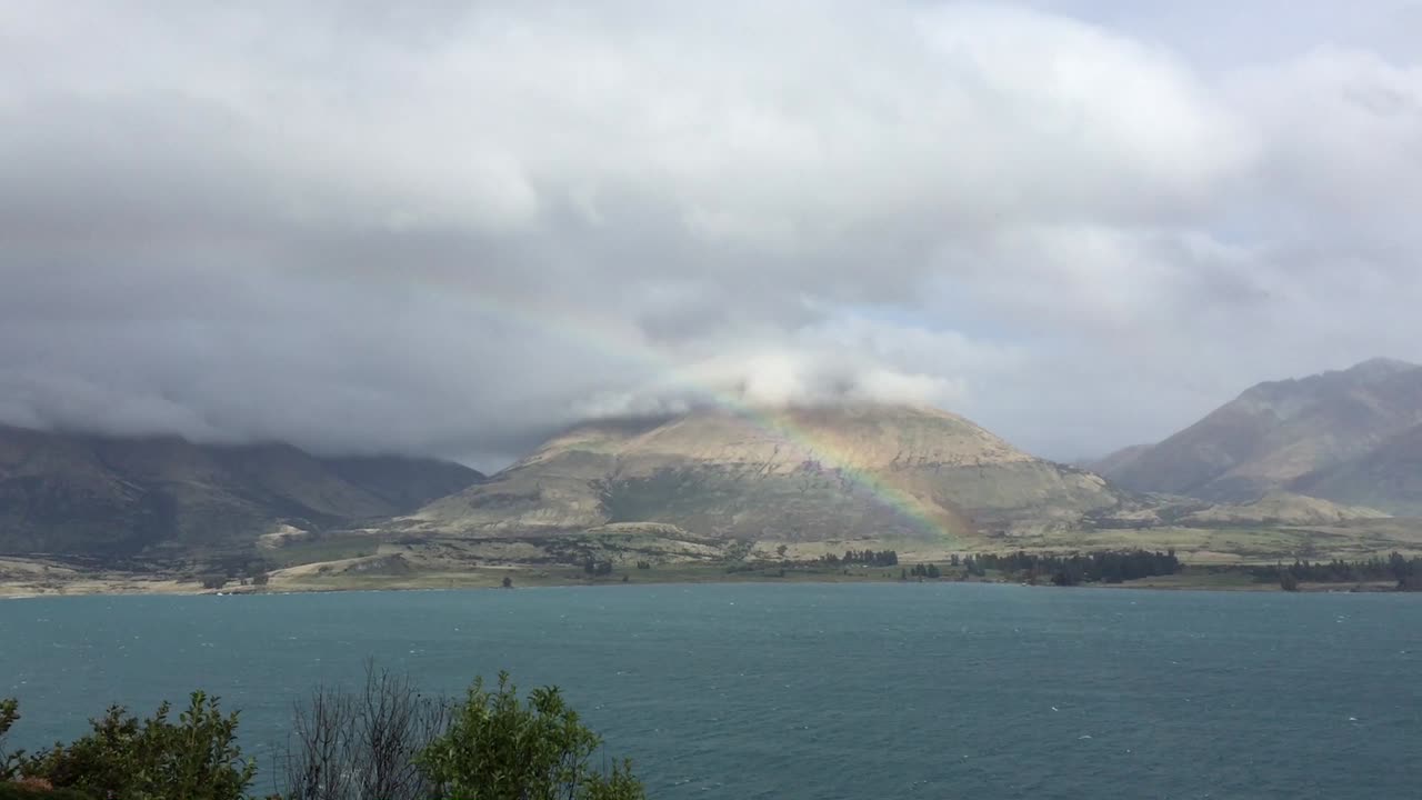 Rainbow over a lake on a cloudy day. in Queenstown, New Zealand.