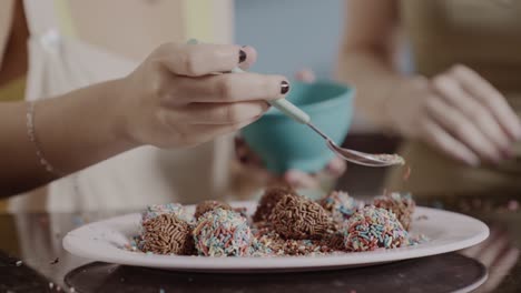 decorating homemade chocolate brigadeiros with colorful sprinkles