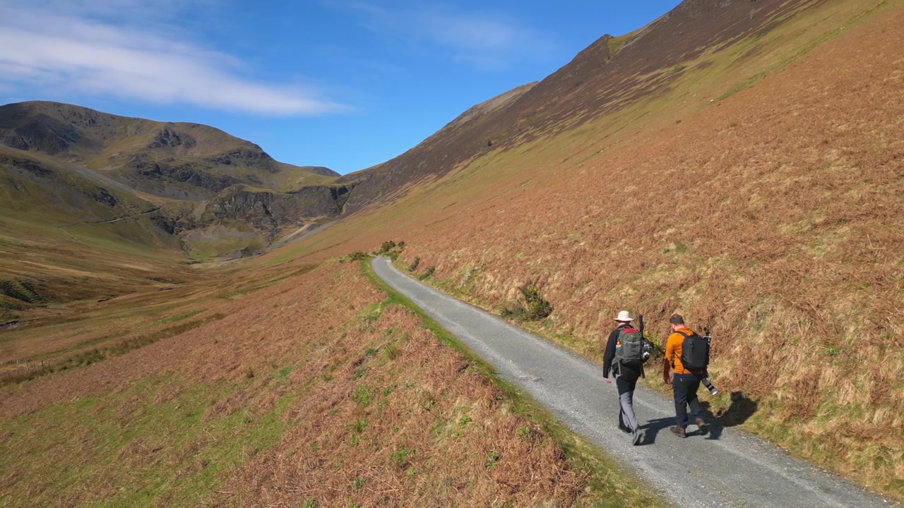 Vandrere går langsomt langs en landlig sti ved Coledale Beck i det engelske Lake District, Cumbria