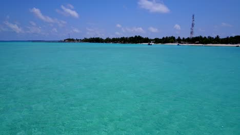 Flying-low-over-spotless-Indian-ocean-waters-towards-island-in-the-Maldives