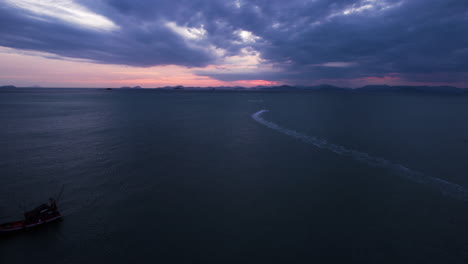 aerial view over moored boats, following a jetski on the open sea, dusk in thailand
