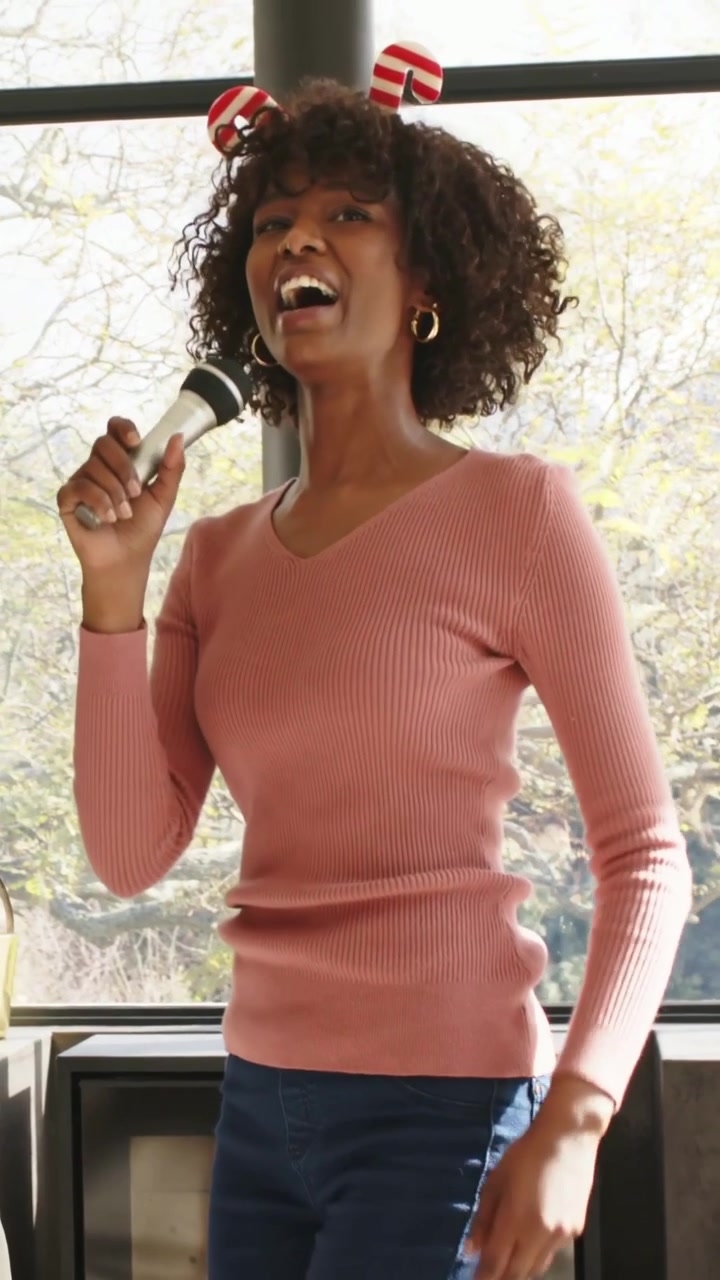 Vertical video: Humming woman wearing pink top red headband lifting mic singing at home for friends