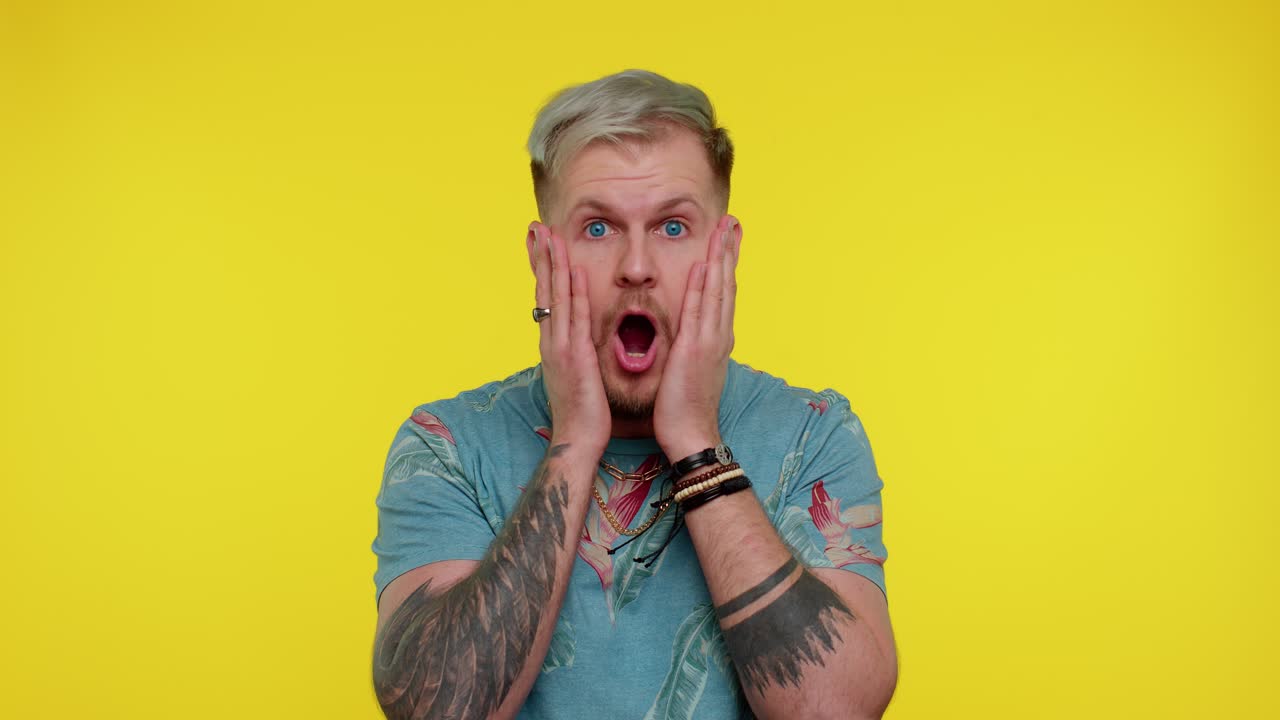 놀라서 흥분한 남자가 커다란 눈으로 카메라를 쳐다보며 놀랐습니다. 갑작스러운 승리에 충격을 받았습니다.