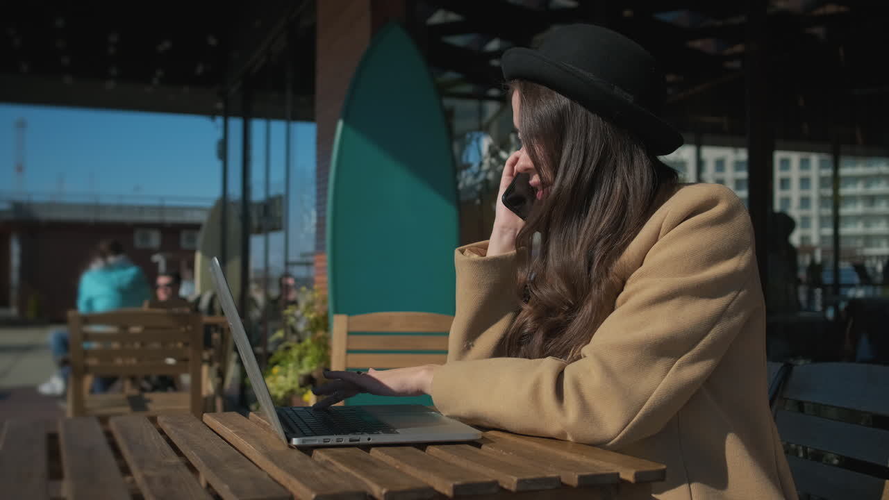 женщина работает на ноутбуке в открытом кафе