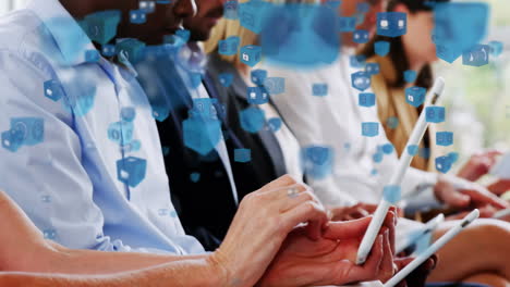 múltiples iconos digitales flotando contra colegas de oficina que usan dispositivos electrónicos