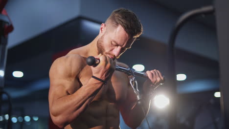 bodybuilder pumping arm muscles. handsome guy with muscular body doing his daily workout to improve his muscles in the gym. close-up.