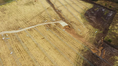 Vista-Aérea-De-Una-Granja-De-Paneles-Solares-Sin-Terminar-En-Un-Gran-Campo-Agrícola-En-La-Naturaleza