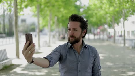 hombre guapo tomando una selfie con un teléfono inteligente al aire libre