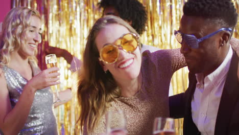 video of two happy diverse couples dancing holding glasses of champagne at a nightclub