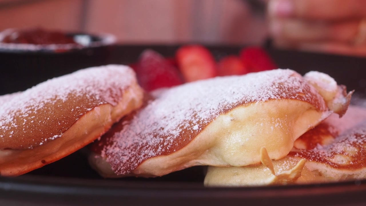 Primo piano di soffici pancake con zucchero a velo e fragole
