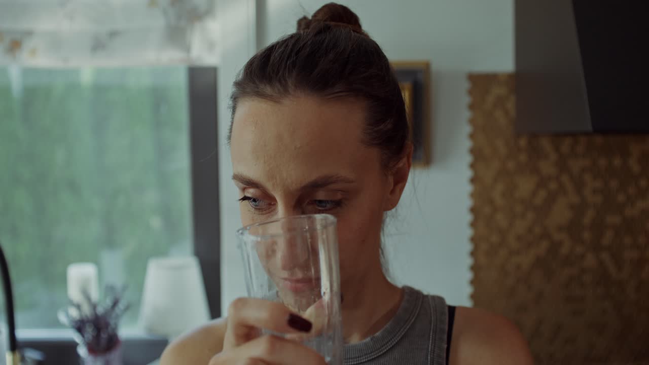 mujer bebiendo agua en la cocina
