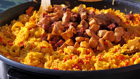 Toma-Secuencia-Haciendo-Una-Deliciosa-Paella,-Agregando-Pollo-Y-Chorizo