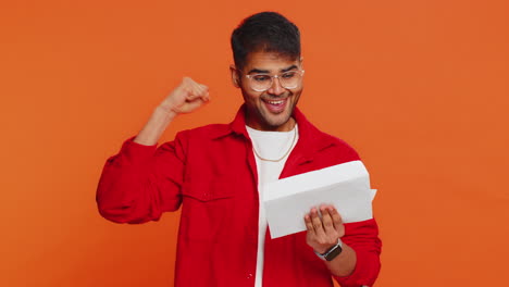 happy indian man open envelope take out letter reads bank loan approve great news award win