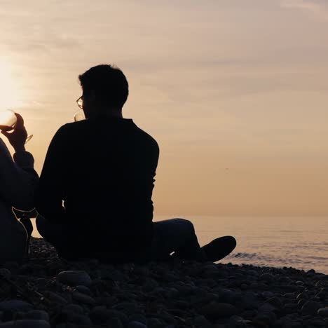Silhouettes-of-a-young-couple-drinking-wine-at-sunset-on-the-shore-of-the-lake-1