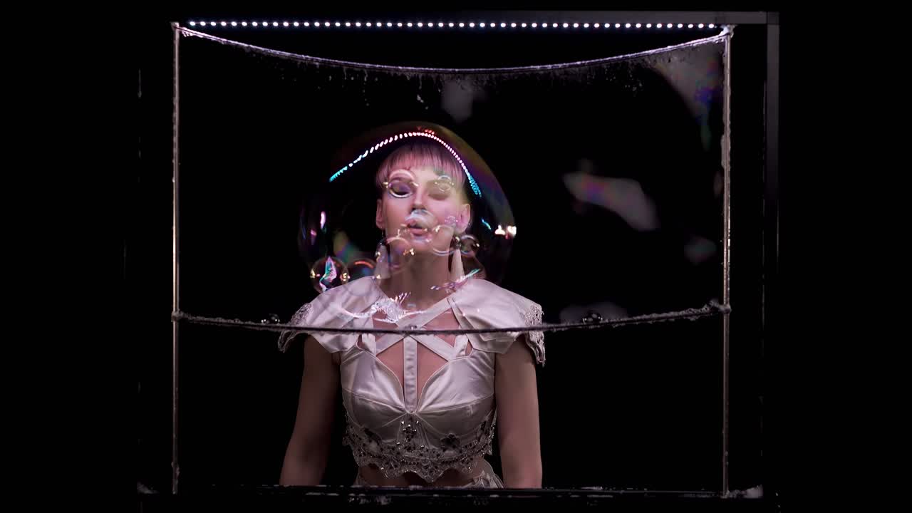 아름다운 소녀는 비누 거품으로 트릭을합니다. 그녀는 비누 스크린에 비누 버블을 불어넣습니다.