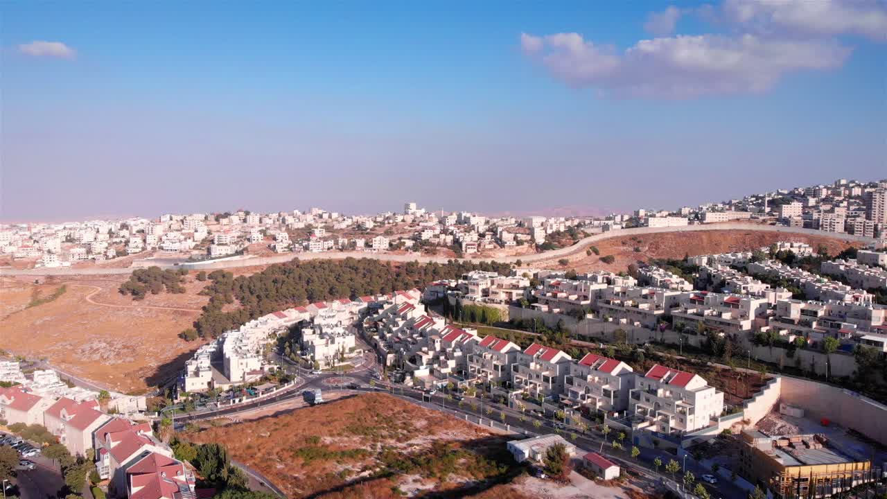 Aerial view of a residential neighborhood and distant urban landscape with a dividing wall