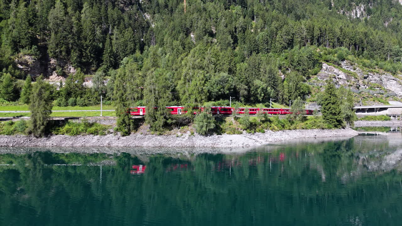 Train reflected in a lake surrounded by trees and mountains