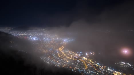 impresionante lapso de tiempo nocturno de la ciudad de bergen con niebla y autos en las calles - estática de la montaña stoltzen con fuegos artificiales ocasionales temprano en la víspera de año nuevo