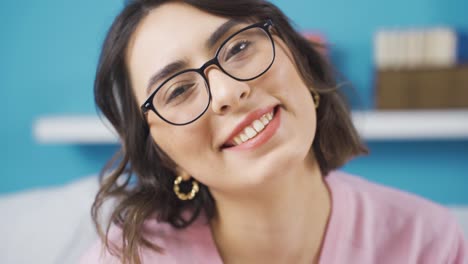 una joven feliz mirando a la cámara en casa, sonriendo.