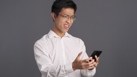 asian man using smartphone and getting upset.