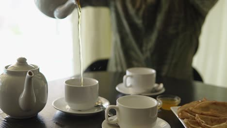 person pouring tea and eating crepes