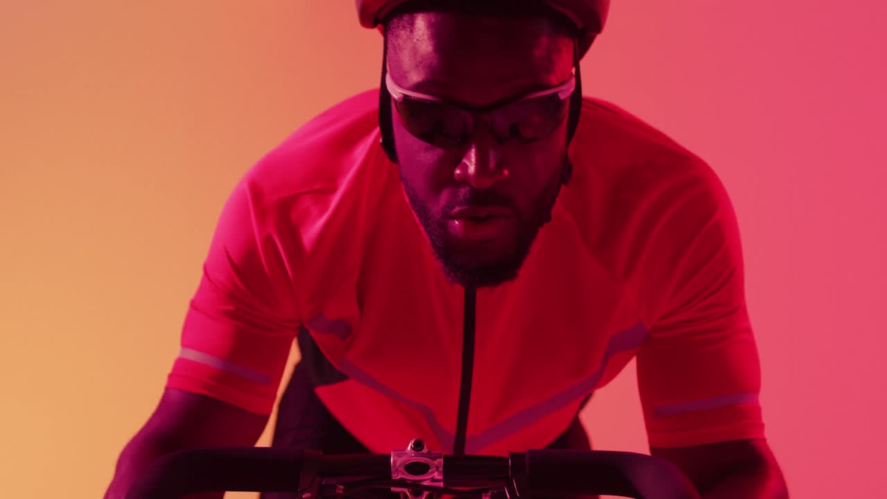 Video af en fokuseret afroamerikansk mandlig cykelrytter, der cykler på neonorange lyn.