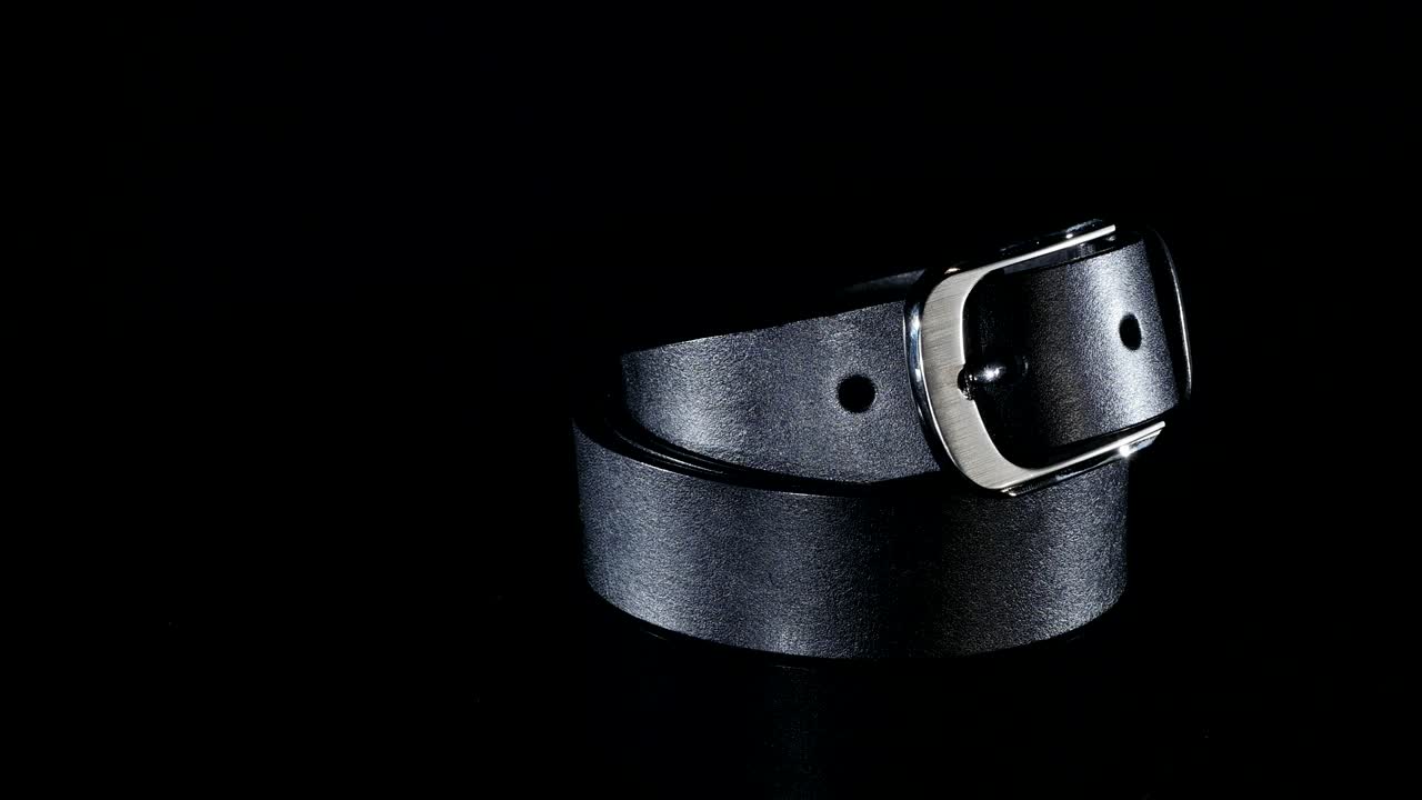 검은색 남성의 벨트는 검은색 배경에 회전합니다.