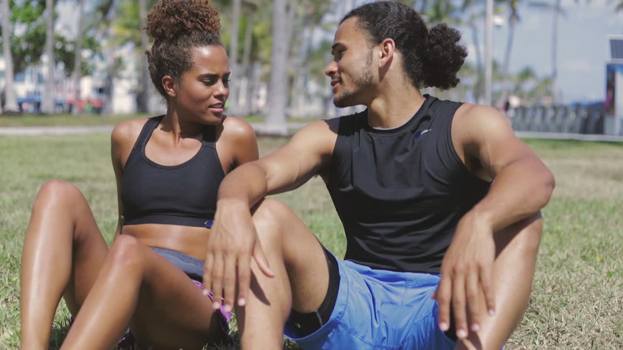 Casal em forma descansando na grama verde