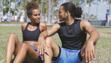 pareja en forma descansando sobre la hierba verde