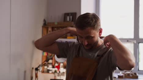 employee puts on protective apron ready for work in studio