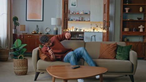 overworked guy lying sofa with cellphone at living room. tired man relaxing