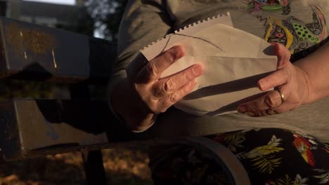 mature woman reading letter sitting on park bench close up panning shot