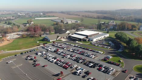 Descending-aerial-of-large-asphalt-parking-lot-and-building-among-rural-rolling-hills-and-countryside-in-USA