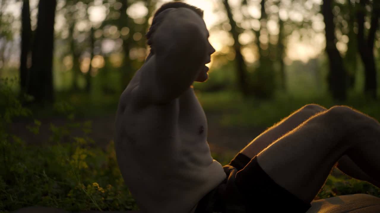 Shirtless man doing sit ups outdoors