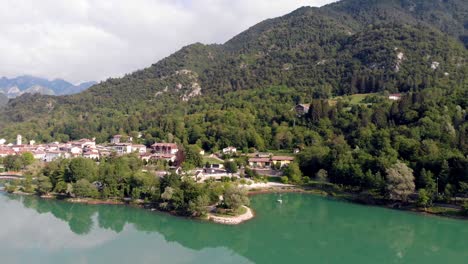 rápida revelación de imágenes aéreas del pueblo barcis en los dolomitas dolomity norte de italia con un gran lago verde azulado y un bote pequeño que refleja