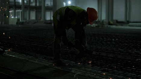 trabajador industrial está cortando barras de refuerzo metálicas con una sierra circular. construcción de una fábrica, hangar