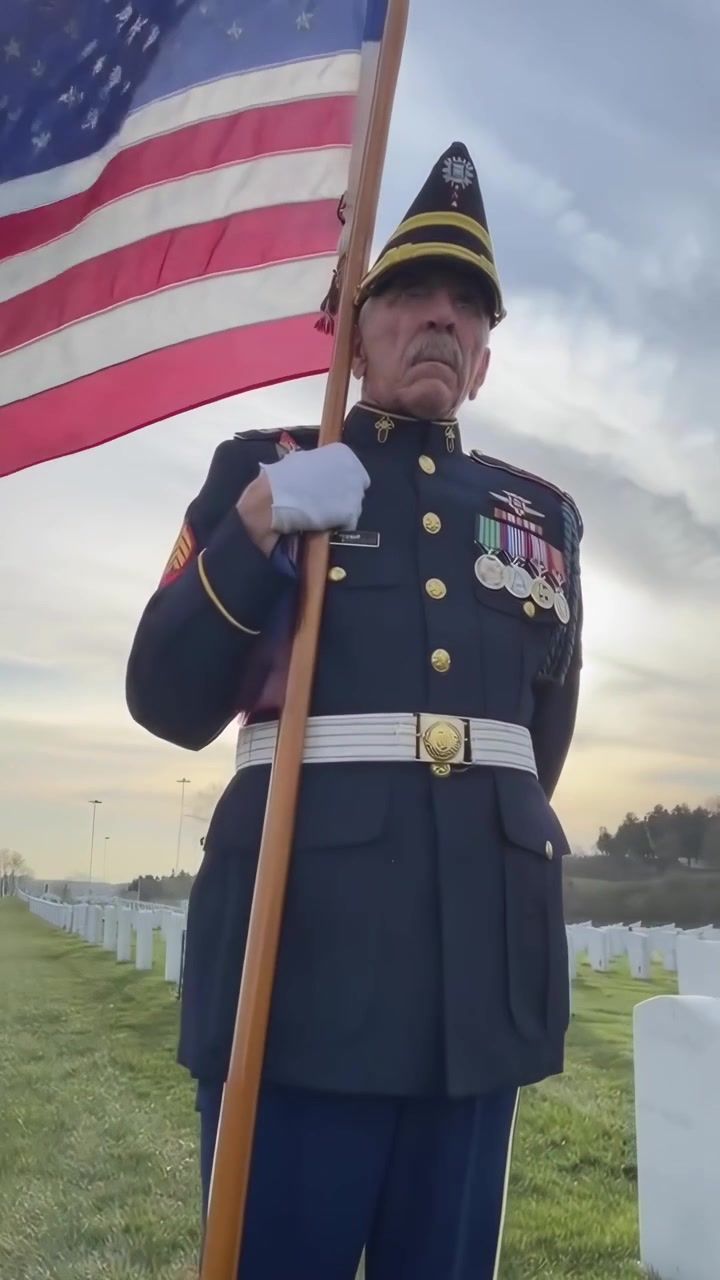 Veteran Standing With American Flag at Military Cemetery