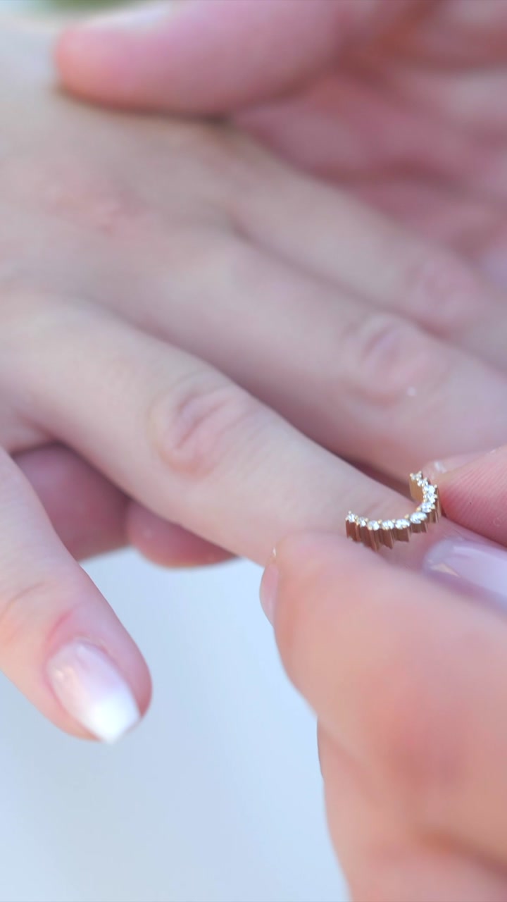groom puts elegant ring on bride finger, closeup slow motion, vertical shot