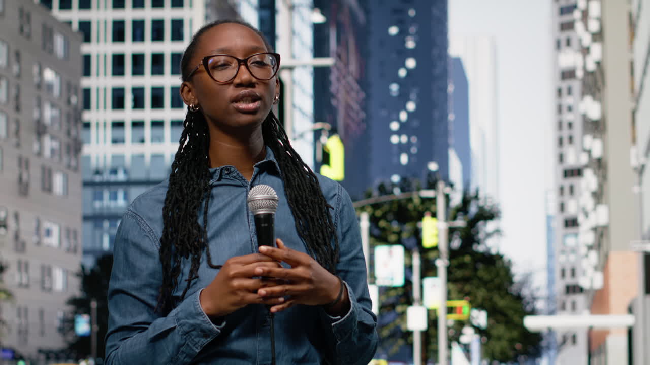Jeune femme reporter présentant des informations au micro, en centre-ville, dans une rue urbaine.