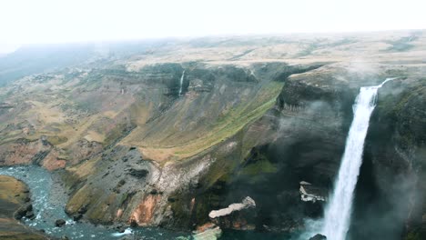 Epic-drone-flight-through-a-canyon-with-a-waterfall-in-Iceland