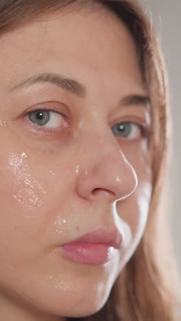 mujer hace un procedimiento de microcorriente en la piel facial moviendo los labios. mujer morena hace movimientos de masaje en la piel usando microcorrientes en la ducha en cámara lenta