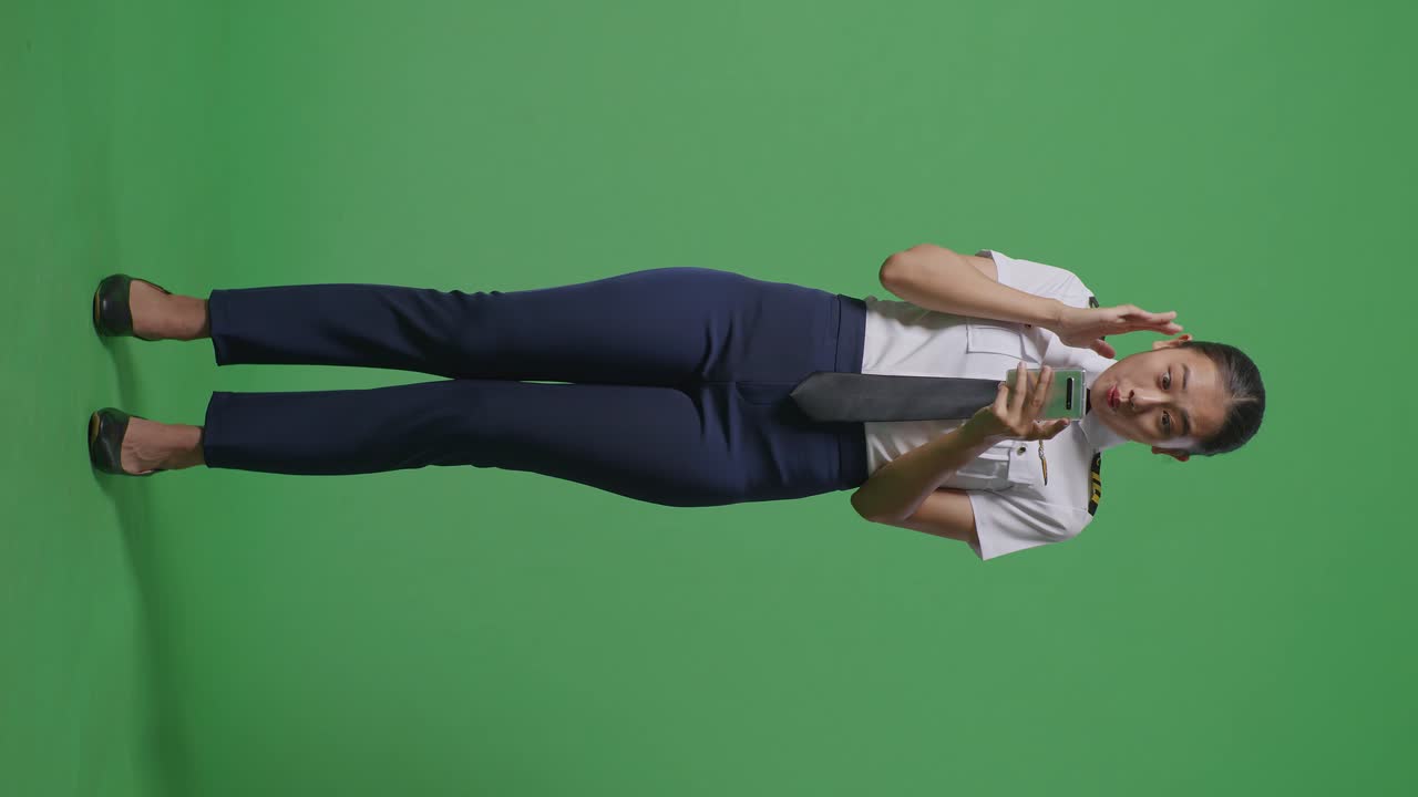 스마트폰을 사용하는 조종사 유니폼을 입은 흥분된 아시아 여성