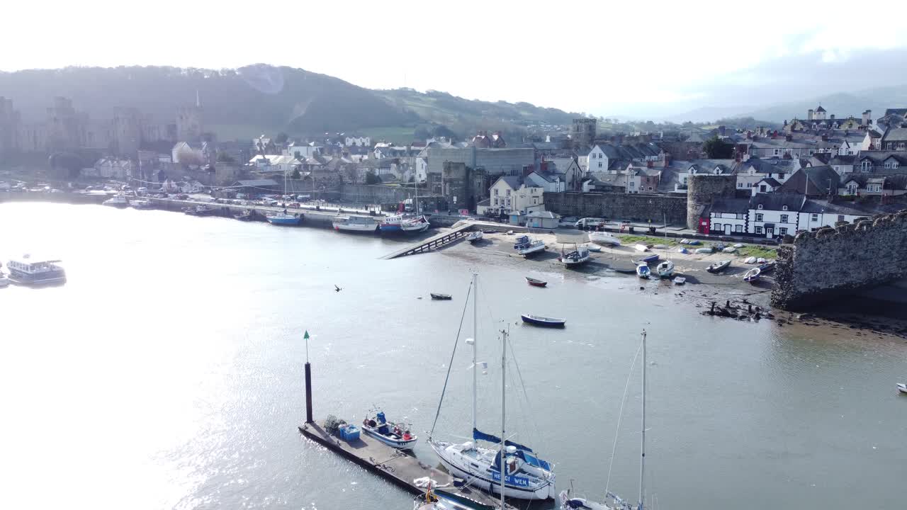 el idílico castillo de conwy y el puerto de la ciudad pesquera, los barcos en la costanera, la antena se eleva lentamente por encima del paisaje urbano.