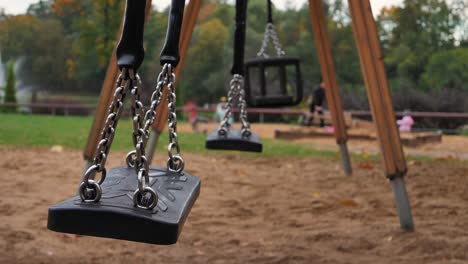 el patio de recreo está cerrado en otoño, primer plano, el columpio se mueve, el columpio está borroso