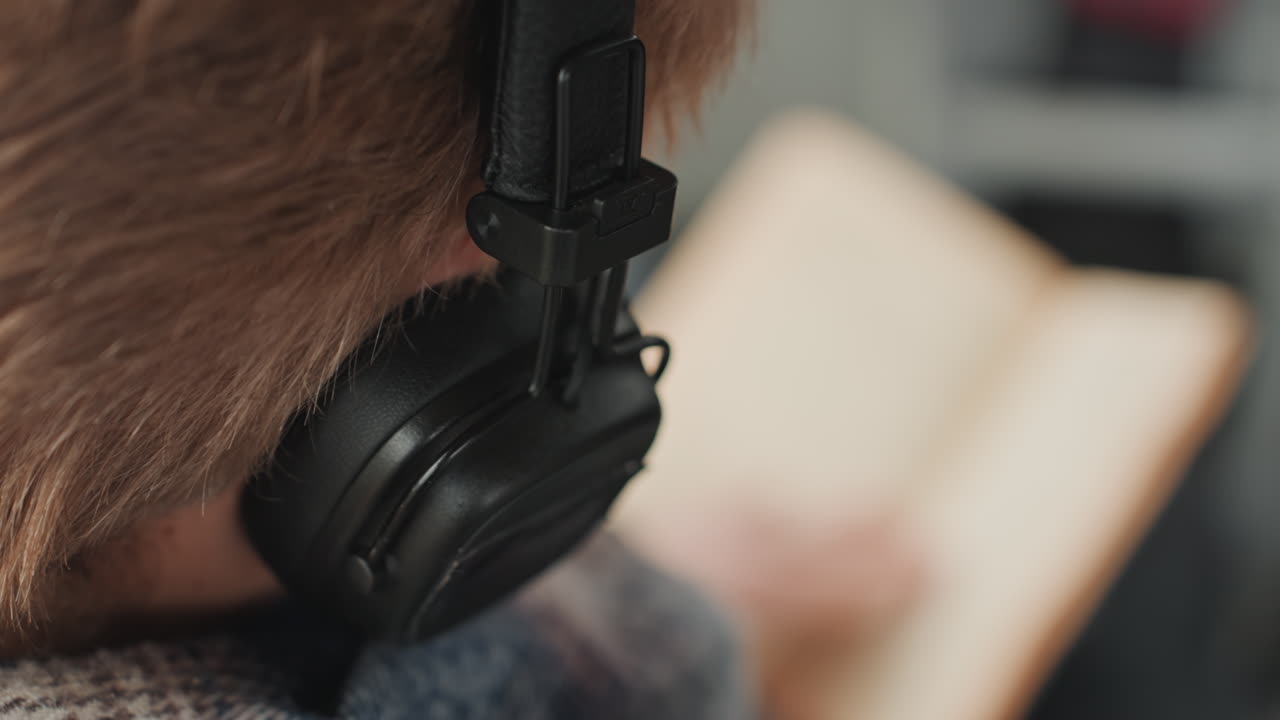 Giovane lettore che si gode la lettura. Uomo con cuffie che legge comodamente. Giovane concentrato che sfoglia le pagine mentre viaggia comodamente. Uomo rilassato ascolta musica e legge un libro tascabile durante il suo tragitto.