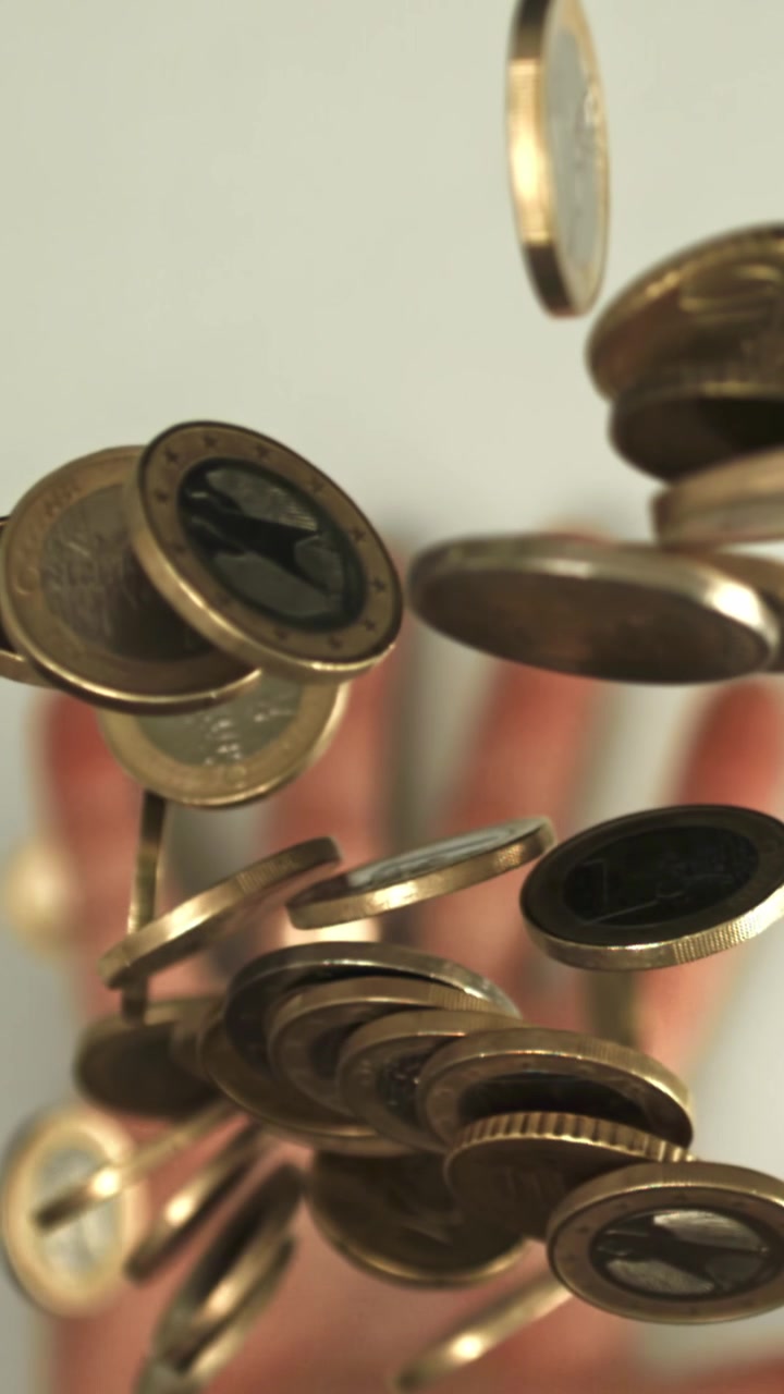 Golden Euro Coins Floating in Slow Motion with a Blurred Hand