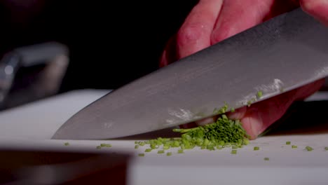 chef chops green onion in kitchen