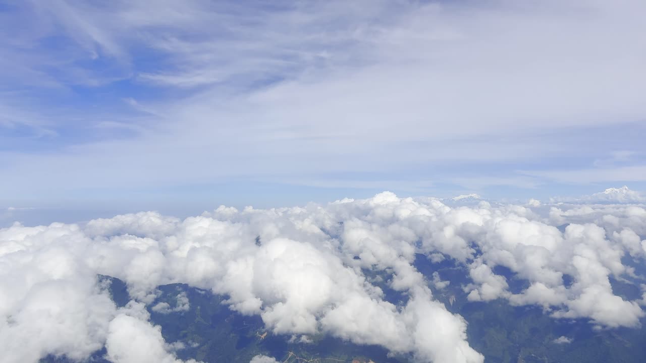 Footage showing clouds in the sky as seen from an airplane window, capturing aerial atmospheric views, soft white formations, and a serene blue horizon, ideal for travel, aviation, and nature visuals