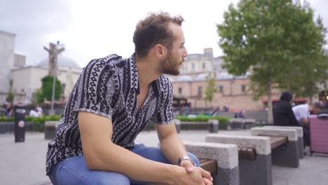 thoughtful young man sitting on bench outdoors.